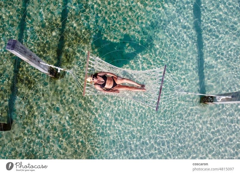 Attraktive Frau entspannt sich in einer Hängematte über dem Wasser. Blick aus der Luft. oben Antenne Air Bucht Strand Bikini blau Windstille Dröhnen Drohnenfoto
