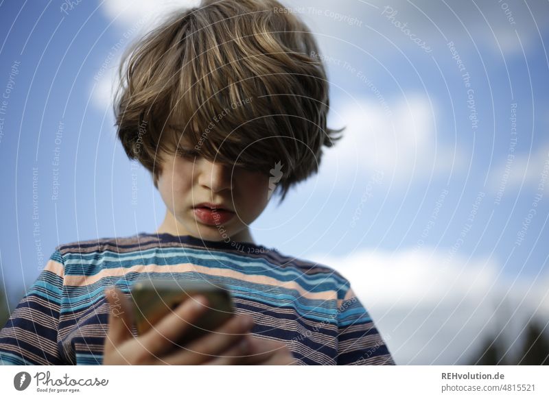Junge schaut auf ein Smartphone Kindheit Gerät digitales Gerät whatsapp Mediennutzung Medienpädagogik Erziehung Handy Konzentration Social Media SMS
