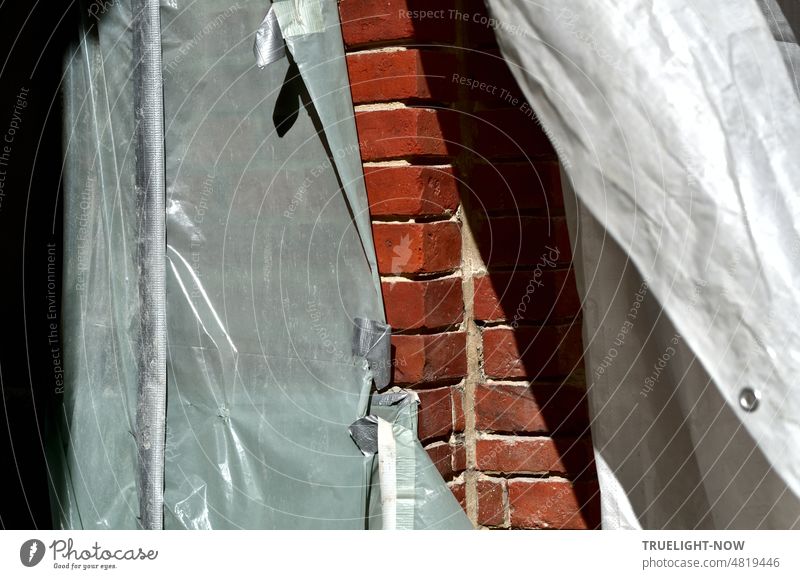 Graue Staubschutz Plane bei der Fassaden Sanierung teilweise geöffnet gibt den Blick frei auf rotes Ziegel Mauerwerk Schutzplane Ziegelsteine Hausecke grau