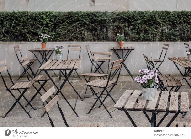 Tische mit Blümchen und Stühle einer Gastronomie im Aussenbereich Stuhl Straßencafé Klapptisch Terrasse Klappstuhl Restaurant Café außengastronomie