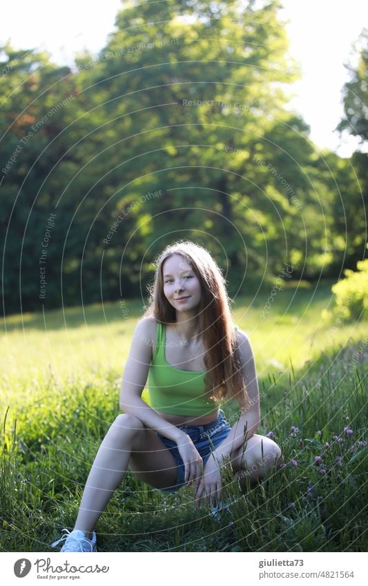 Sommerliches Porträt eines langhaarigen Teenager Mädchens mit kurzen Jeansshorts und bauchfreiem Top im Park Mensch Junge Frau Jugendliche 13-18 Jahre