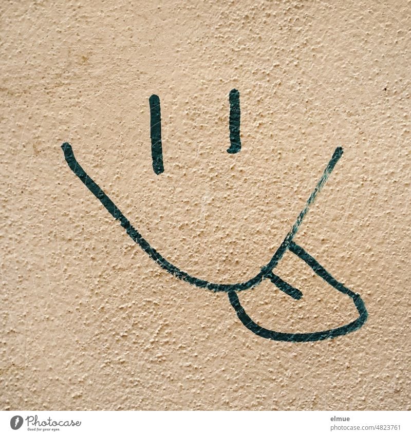 gespraytes stilisiertes Gesicht mit Strichaugen und rausgestreckter Zunge an einer verputzten Hauswand / Graffiti / Einstein Graffito rausstrecken