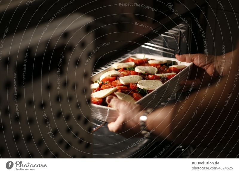 Auflauf wird in den Ofen geschoben Auflaufform kochen & garen Essen Zubereitung von Speisen lecker Lebensmittel Hände Backofen Küche Mozzarella Tomaten Käse