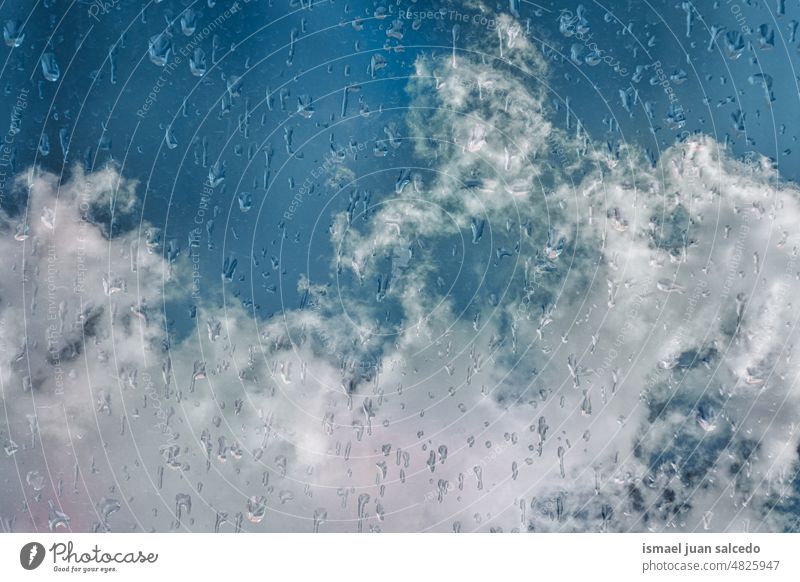 Tropfen auf dem Fenster und blauer Himmel im Hintergrund Regentropfen Wasser nass Glas Blauer Himmel Wolken durchsichtig Oberfläche Nahaufnahme abstrakt
