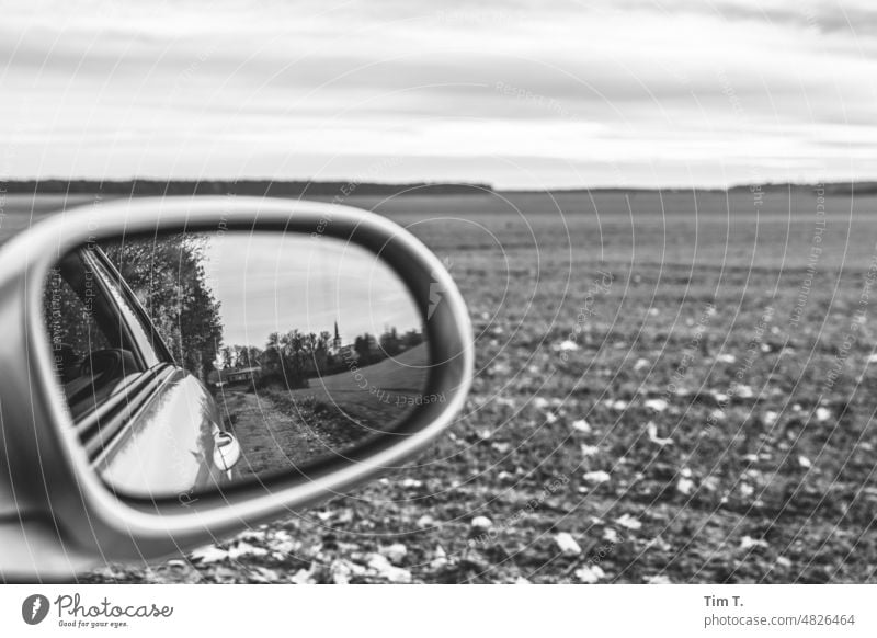 Blick durch den Seitenspiegel Feld Dorf Autofahren Spiegel s/w Ackerland Brandenburg b/w Schwarzweißfoto b&w ruhig Tag Menschenleer Außenaufnahme Einsamkeit