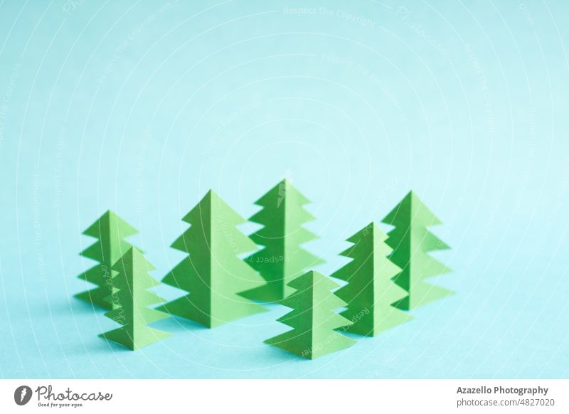 Grüne Papierbäume auf blauem Hintergrund mit freiem Platz zum Kopieren und Einfügen. Origami Wald Baum abstrakt Konzept konzeptionell kreativ Design ökologisch