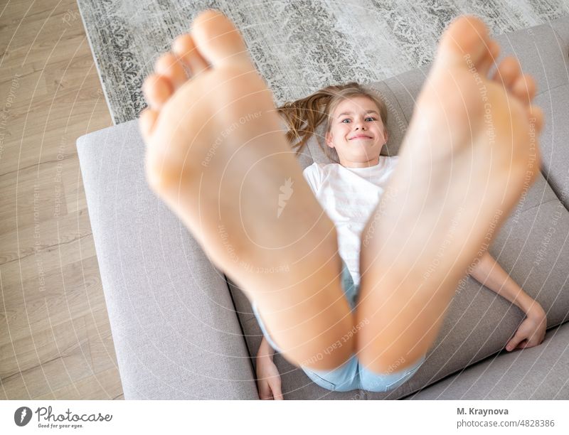 Preteen Mädchen liegend auf Couch mit ihren nackten Füßen Anhebung bis hoch Fuß Erholung Barfuß Person Kind Bett bequem aussruhen Frau Glück heimwärts Morgen