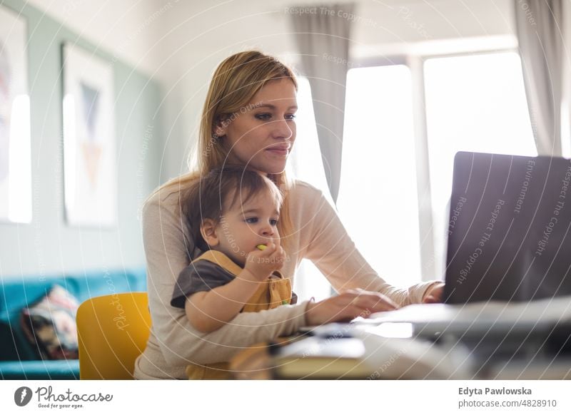 Mutter arbeitet am Laptop mit Kind auf dem Schoß Erwachsener Zuneigung Baby Bonden Junge offen Pflege Kindheit heimisch genießend Familie Spaß Fröhlichkeit