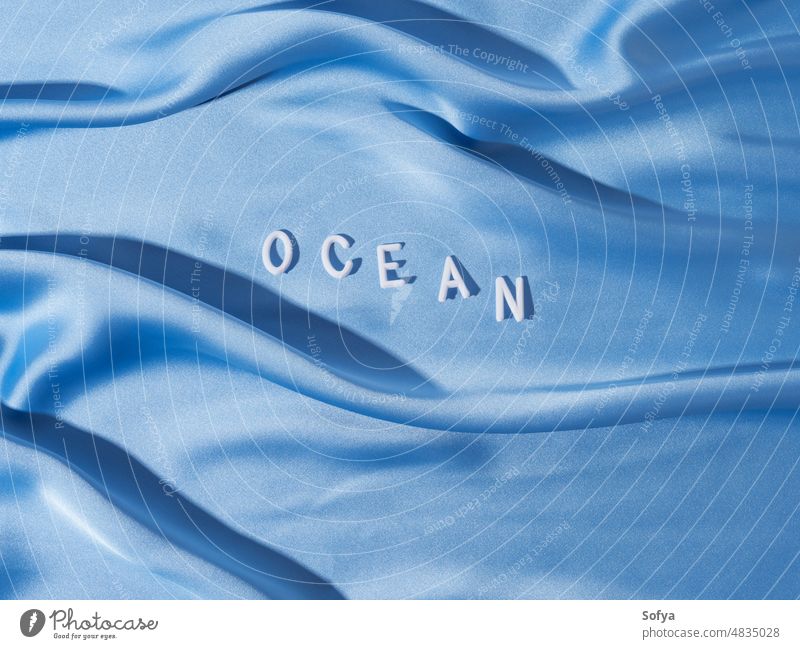 Weltmeer in weißen Buchstaben auf blauem Wellentextil Meer Tag Wort winken Wasser Textil 8. Juni Oberfläche Konzept MEER Feiertag Erde Schutz unter Wasser