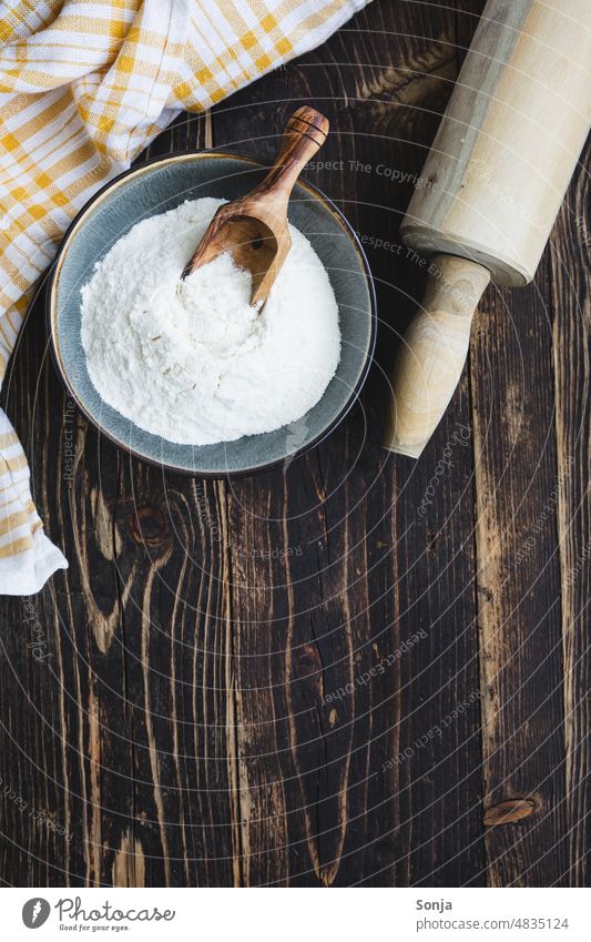 Draufsicht auf eine Schüssel Mehl und ein Nudelholz. Rustikaler Holztisch. Tisch rustikal Backwaren backen Vorbereitung brot backen weiß Zutaten Lebensmittel