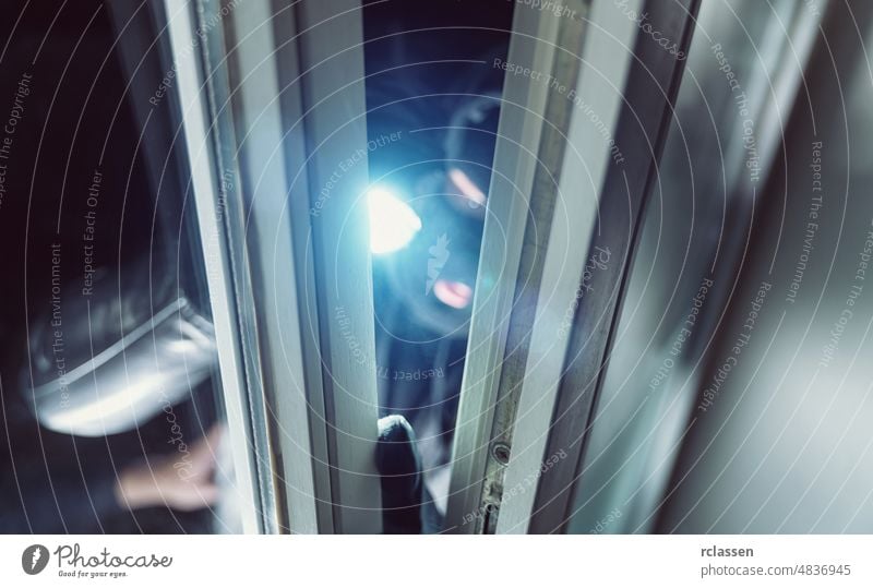 Einbrecher leuchtet nachts mit einer Taschenlampe in ein Fenster eines Hauses Polizei Appartement stehlen weiß Überfall Werkzeug Hauseinbrecher Konzept Pause