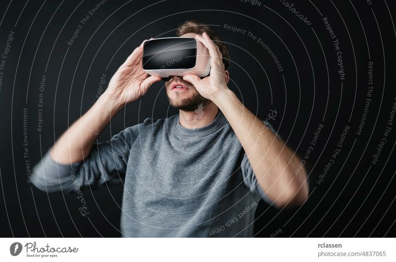 junger Mann trägt Virtual Reality-Brille VR-Headset auf schwarzem Hintergrund Business digital Entertainment Spiel Spielen Inbetriebnahme Innovation Realität