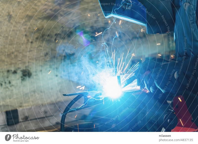 Schweißer schweißt Metallteil in Autowerkstatt Schweißnaht Sicherheit Fähigkeit technisch Konstruktion Arbeitsplatz Herstellung Gerät manuell Mann Industrie