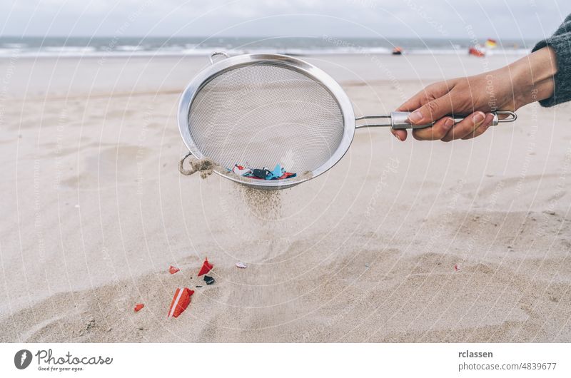 Junge Frau reinigt Mikroplastik aus dem Sand am Strand, Umweltproblem, Verschmutzung, Ökosystem und Klimawandel-Warnkonzept Kunststoff Hand marin Europa Afrika