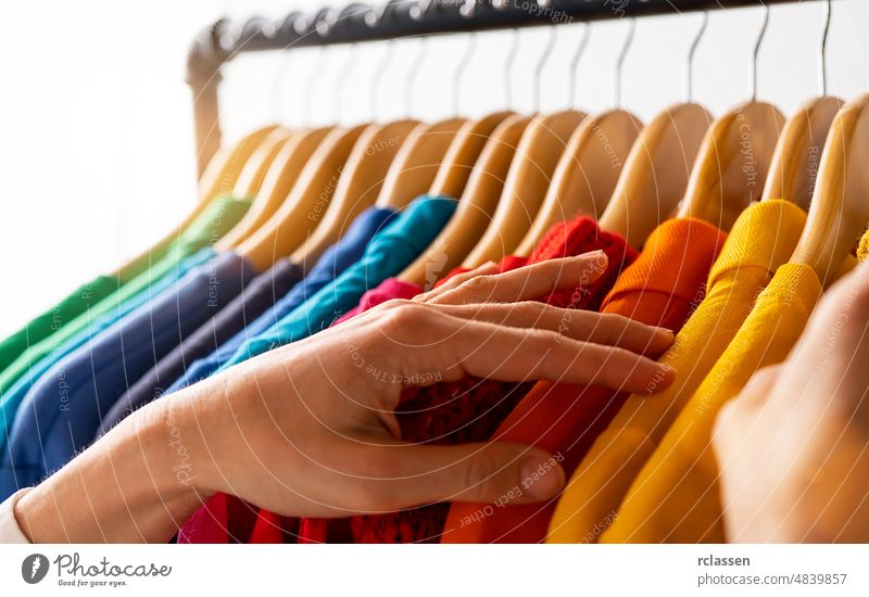 Mode Kleidung hängen auf Kleiderständer - helle bunte Regenbogen Auswahl an Kleidung Schrank. Frau wählen Outfits auf Kleiderbügeln im Laden Schrank. LGBT Farben
