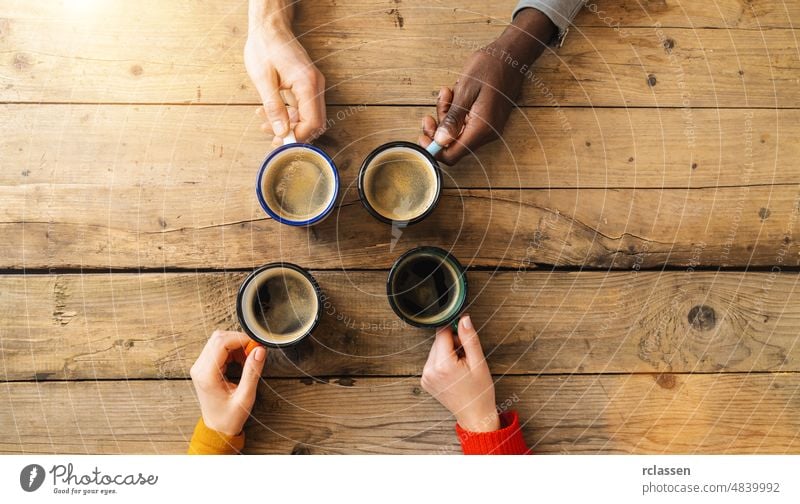 Gruppe von Freunden trinkt Kaffee in einem Bar-Restaurant - Menschen Hände jubeln und Toast auf Top-Ansicht Punkt - Social gathering Konzept mit weißen und schwarzen Männern und Frauen zusammen