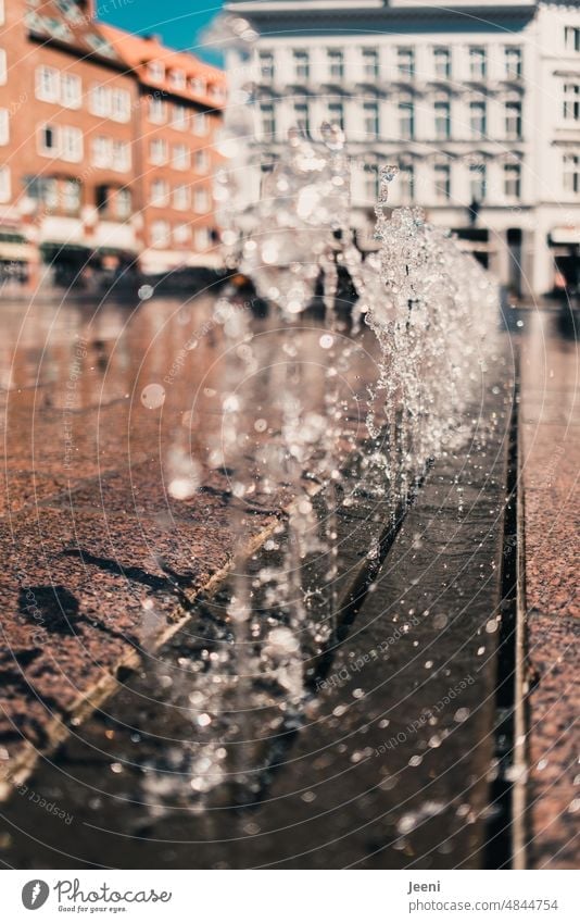Springbrunnen auf einem Marktplatz Wasser Wassertropfen Tropfen Wasserfontäne nass sprudelnd spritzen frisch kalt Erfrischung Stadt Sommer Abkühlung Sonnenlicht