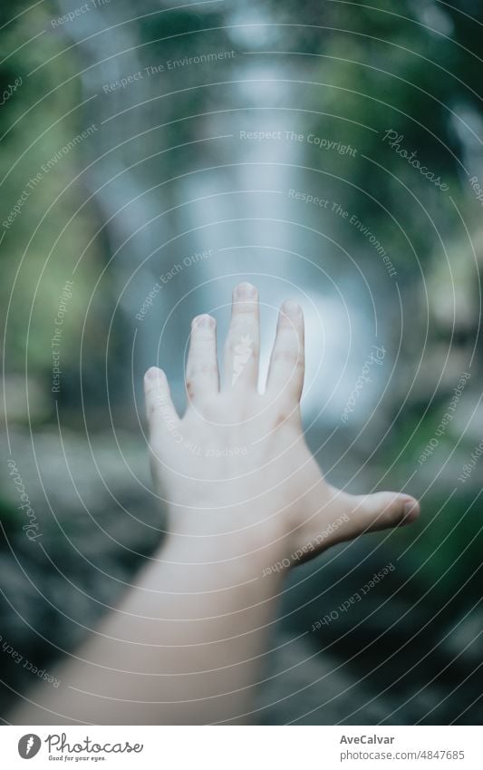 Moody Bild eines selektiven im Fokus Hand vor einem Wasserfall während eines sonnigen Tages, friedliche Szenario, Kopie Raum. Hilfe und Selbsthilfe-Konzept, psychische Gesundheit Konzept. Therapie und Suche nach Hilfe