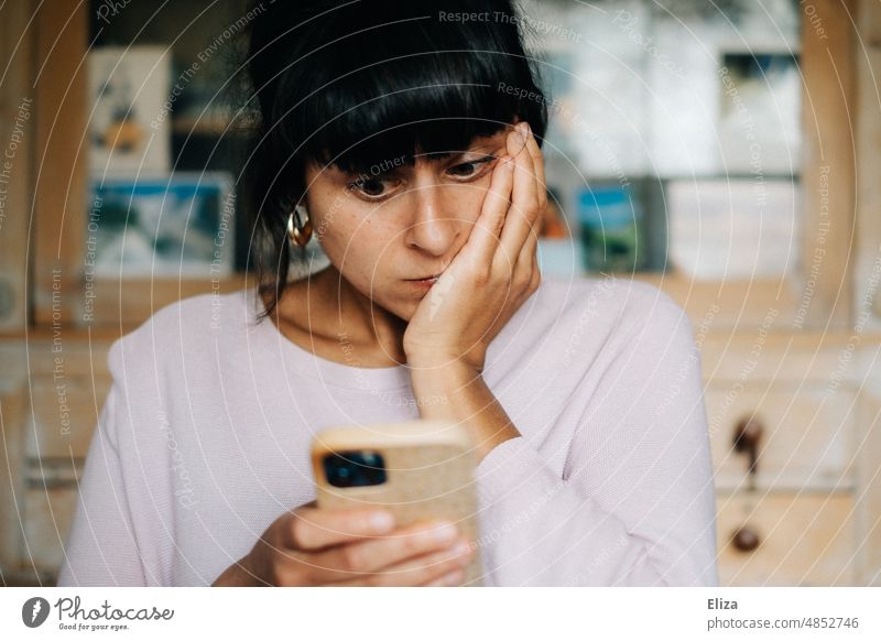 Junge Frau guckt auf ihr Smartphone und ist besorgt Schock schlechte Nachrichten Schrecken Verzweiflung Angst Panik Entsetzen Handy erschrecken börsencrash