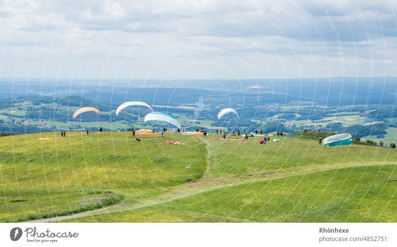 Gleitschirmflieger auf der Wasserkuppe warten auf den perfekten Wind Drachenfliegen Drachenflieger Himmel Außenaufnahme Farbfoto Tag Wolken Textfreiraum oben