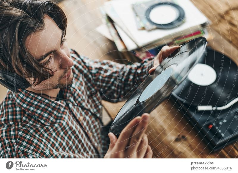 Mann hört Musik von einer Schallplatte. Abspielen von Musik von einer analogen Platte auf einem Plattenspieler. Genießt Musik aus einer alten Sammlung. Retro und Vintage