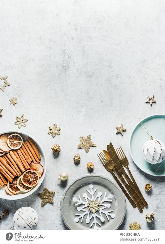 Weihnachten Hintergrund mit Tischgedeck, Teller, goldene Besteck, Dekoration und Tanne grün, Schnee und Zimtstangen, Kugeln auf Betonhintergrund. Festliches Abendessen Hintergrund.