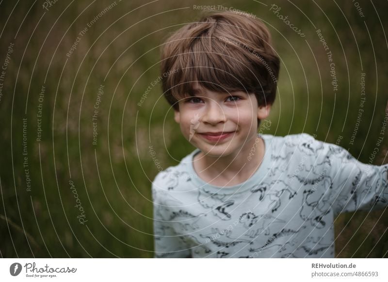 Junge grins in die Kamera Kind Mensch Kindheit Lächeln natürlich Zufriedenheit Blick in die Kamera Porträt Oberkörper Blick nach vorn Zentralperspektive Tag