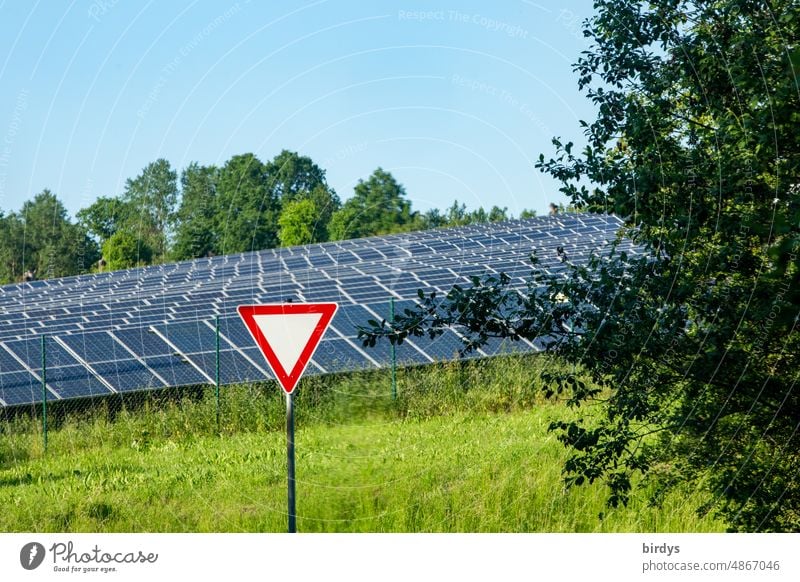 Vorfahrt - achten - Schild vor einer PV-Freiflächenanlage , Photovoltaik- Freiflächenanlage vor wolkenlosem Himmel, PV-Module PV-Anlage grüner strom nachhaltig