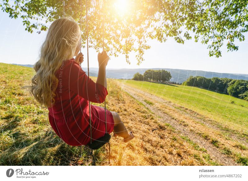 schöne junge Frau auf einer Schaukel an einem Sommertag im Freien pendeln Mädchen blond Baum Person Cloud Park Fliege Eifel rot Erwachsener Freude Aktivität