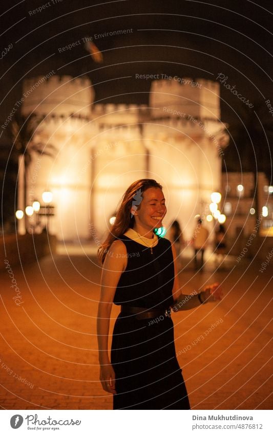 Glückliche Frau zu Fuß im historischen Zentrum der Stadt mit Lichtern. Glücklich lächelnd, auf dem Weg zur Party. Junge und schöne Touristin in Spanien. Nacht