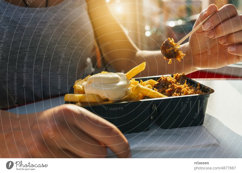 Deutsche Currywurst mit Curryketchup, Röstzwiebeln und Pommes frites mit Mayonnaise in der Stadt Lebensmittel Ketchup Deutschland Markt Sonnenlicht Barbecue
