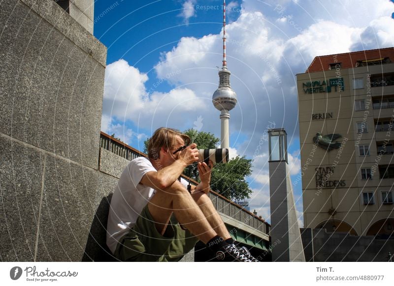 ein Mann fotografiert im Sitzen an der Spree sitzen Fernsehturm Fotografieren Objektiv Canon Berlin Mitte Sommer Berlin-Mitte Berliner Fernsehturm Hauptstadt