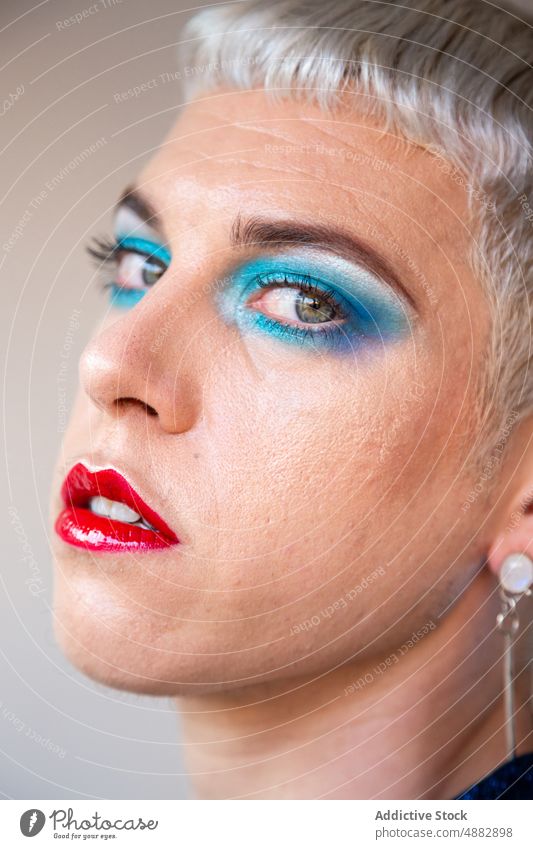Porträt eines Transgender-Mannes mit Make-up Lidschatten schwul posierend queer Mode Individualität lgbtqi Nahaufnahme Stolz Studioaufnahme feminin rot