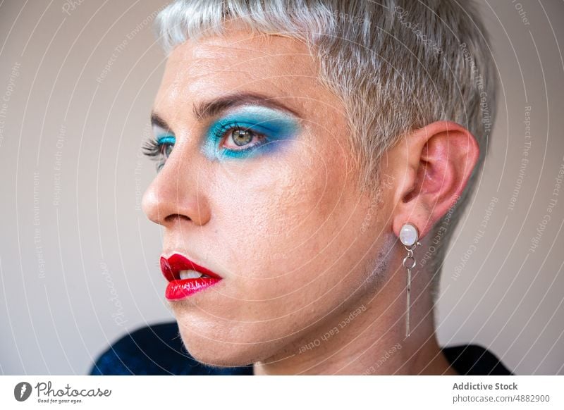 Porträt eines Transgender-Mannes mit Make-up Lidschatten schwul posierend queer Mode Individualität lgbtqi Nahaufnahme Stolz Studioaufnahme feminin rot