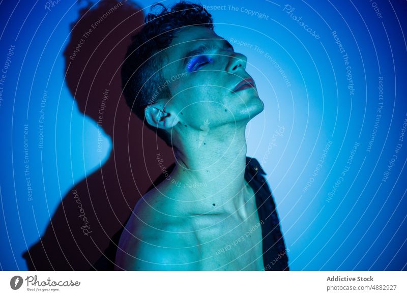 Transgender mit Lidschatten posiert auf beleuchtetem Hintergrund schwul Augen geschlossen posierend Make-up queer Mode Individualität lgbtqi Stolz