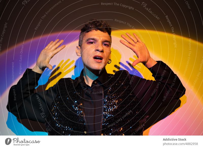 Trendy Homosexuell Mann posiert in beleuchteten Hintergrund androgyn posierend Mode selbstbewusst Porträt Hand modisch trendy Kleidung glänzend Party