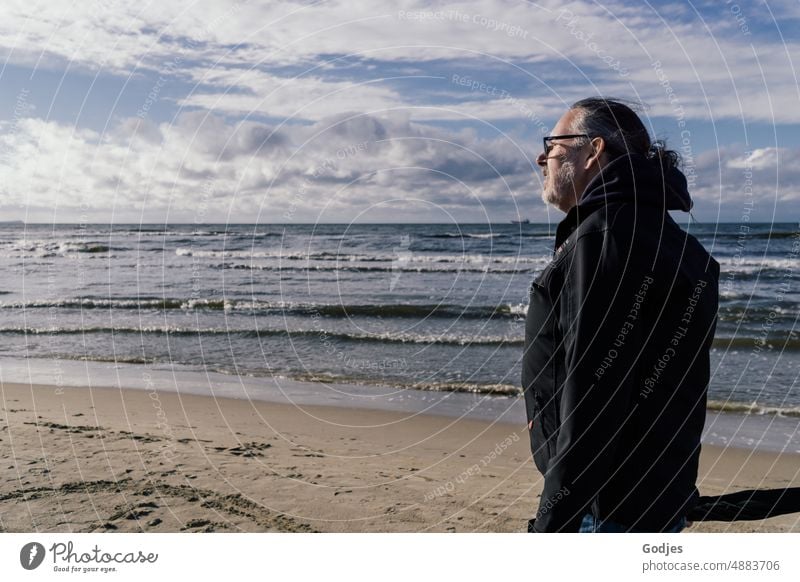 Älterer Mann in Windjacke geht am Strand entlang Ferien & Urlaub & Reisen Meer Sand Wasser Mensch Sonne Himmel Sommer Einsamkeit Küste Wellen Wolken Horizont