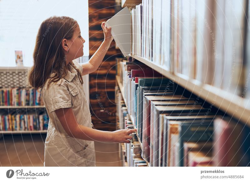 Schulmädchen wählt Buch in Schulbibliothek. Kluges Mädchen wählt Bücher aus. Lernen aus Büchern. Schulische Bildung. Vorteile des täglichen Lesens. Kindliche Neugierde. Zurück zur Schule