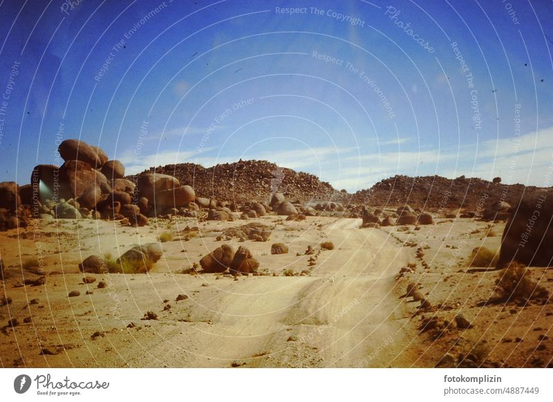 sandiger Weg durch eine felsige Wüste Sand Felsen Sahara Steine Piste trocken Safari wüst Afrika Natur Landschaft Außenaufnahme Abenteuer Cockpit