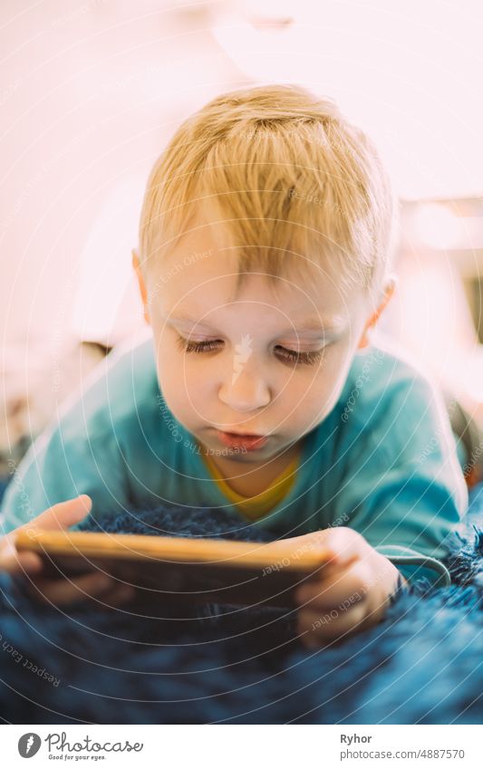 Kleiner blonder Junge spielt Spiele am Telefon authentisch schön beschäftigt sorgenfrei Kaukasier Kind Kindheit Bildung begeisterte Spaß Generation Glück liegen