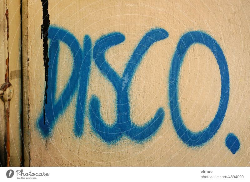 Tatort I DISCO. steht in blau an einer verputzten Hauswand / Graffiti Disco Disko Mitteilung Schriftzug Schmiererei Kleinkunst Fassade Jugendkultur Subkultur