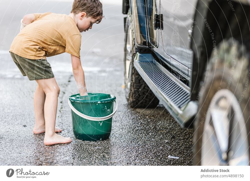 Kaukasischer Junge wäscht Auto mit Seife Sauberkeit Waschen PKW Eimer Schwamm Sud schäumen Seifenschaum Lifestyle Stehen außerhalb Selbstbedienung Aktivität