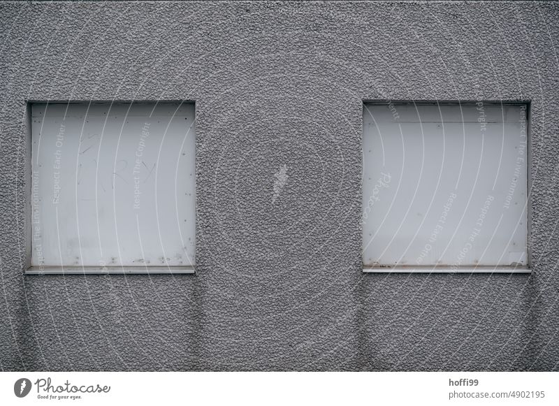 zwei geschlossene Rollläden auf einer grauen schäbigen Fassade Tristesse Depression deprimiert Rollladen trist Fenster Gebäude Mauer Jalousie geschäftsaufgabe