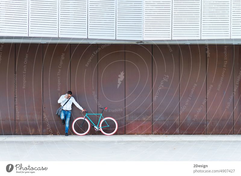 Junger Mann mit Sonnenbrille stehend beim Telefonieren Fahrrad Stehen Textfreiraum urban Mitteilung Umhängetasche Aufruf Smartphone Anruf Funktelefon Zelle