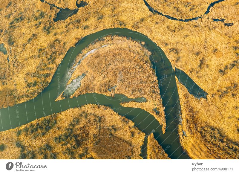 Luftaufnahme von trockenem Gras und teilweise gefrorenen Fluss Landschaft im Spätherbst Tag. High Attitude Ansicht. Sumpf Moor. Drone Ansicht. Ansicht aus der Vogelperspektive