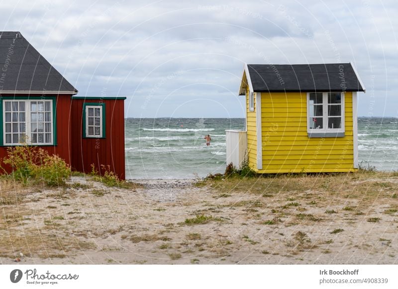 bunte Badehäuser mit Badendem im Hintergrund in den Wellen Sonnenlicht Textfreiraum oben Außenaufnahme Farbfoto strandlage Ærø Strandhaus Strandspaziergang