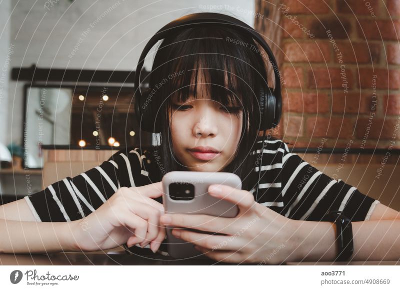 Teenager-Mädchen trägt Kopfhörer und hält ein Handy Smartphone Social Media entspannt auf dem Sofa. Musik Telefon hören Person Mobile Frau jung Glück Gesang