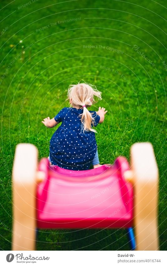 Kind auf der Rutsche im Garten rutschen spielen Spaß bewegung Spielplatz Rasen Mädchen Freude Kindheit Fröhlichkeit