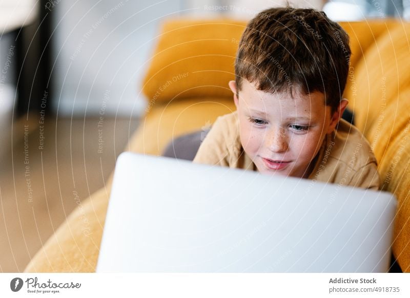 Junge auf einem Sofa liegend, der den Laptop benutzt Kind Computer Glück Kaukasier Technik & Technologie männlich Lächeln im Innenbereich heimwärts Kindheit