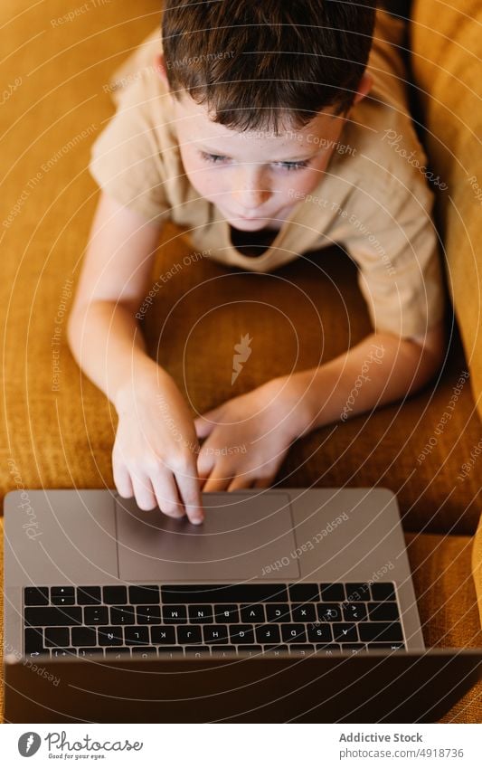 Junge auf einem Sofa liegend, der den Laptop benutzt Kind Computer Kaukasier Technik & Technologie männlich im Innenbereich heimwärts Kindheit wenig Spiel